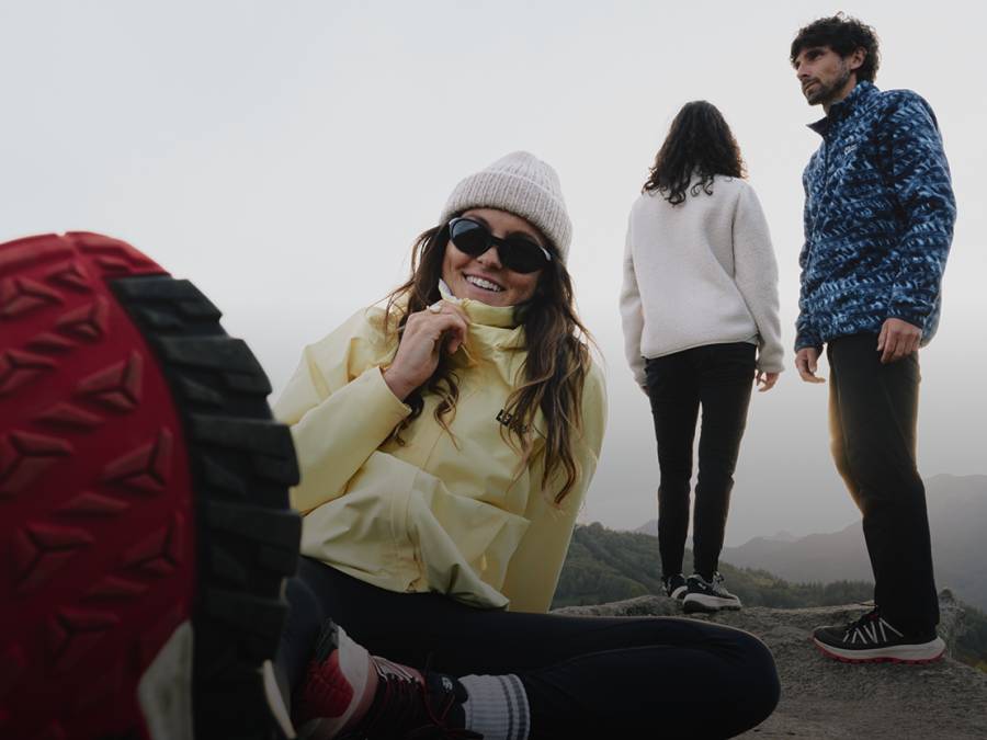 Young woman in sporty hiking gear crouches on a rock in the darkness