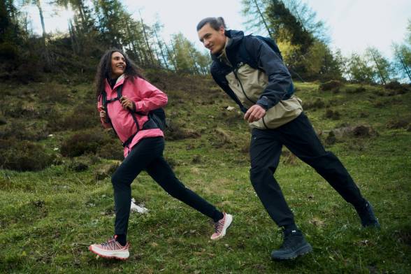 A couple dressed in sporty hiking gear are walking across a&nbsp;clearing