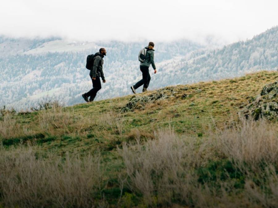Two people in autumnal hiking gear are crossing a&nbsp;mountain