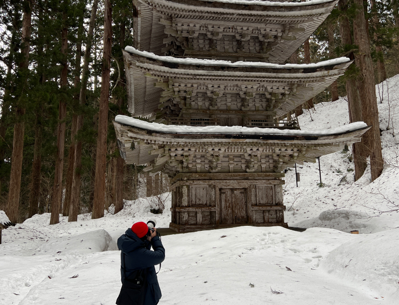 Yuto in the snow taking a photo of a pagoda