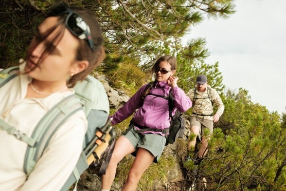 A couple dressed in sporty hiking gear are walking across a&nbsp;clearing